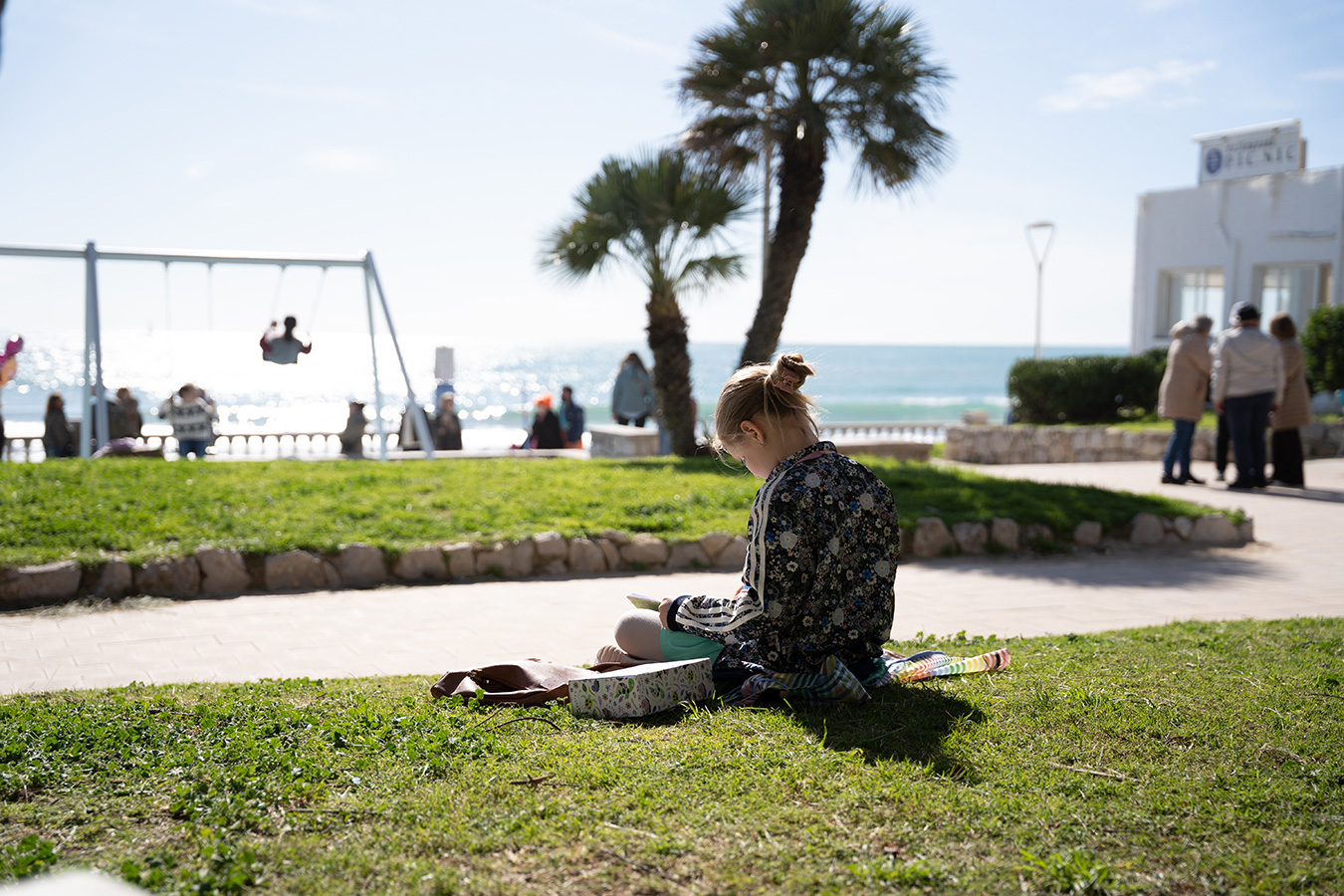 Candid photo of a child reading in a seaside park in Barcelona