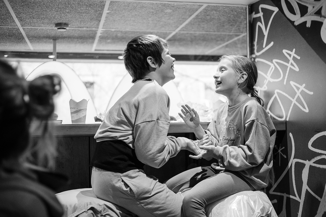 Black and white candid photo of two children laughing together