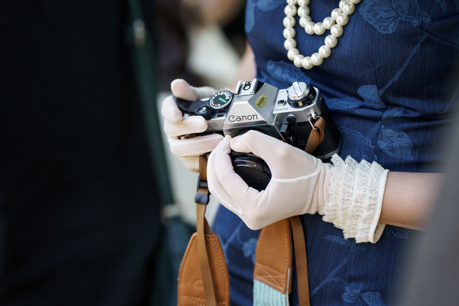 Detail photo of gloved hands holding a vintage Canon camera during a senior portrait session